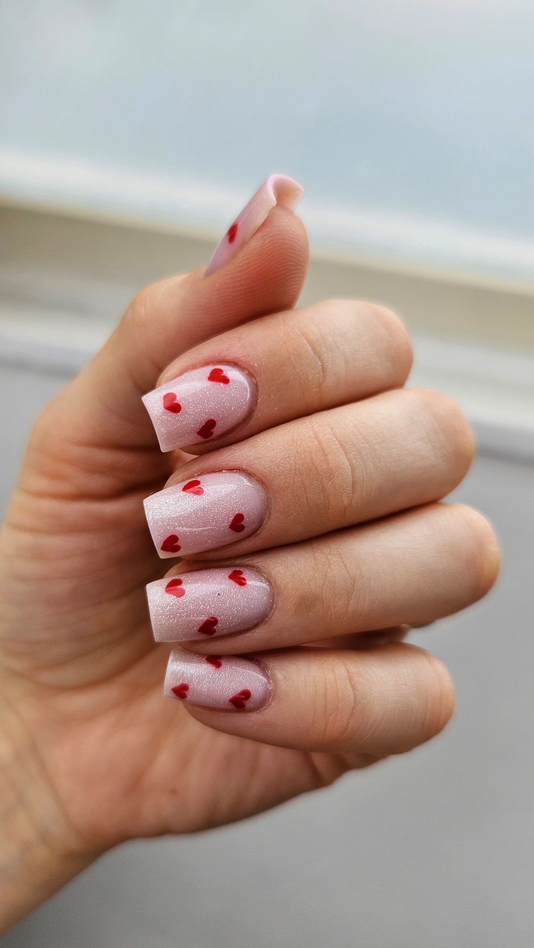 Lichtroze vierkante nagels met kleine rode hartjes